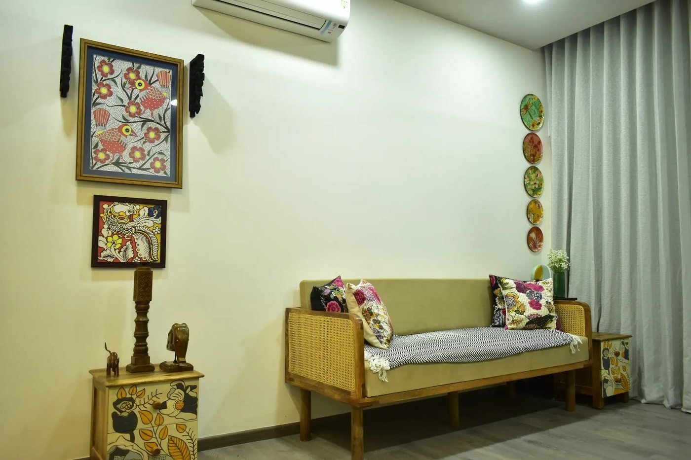Cane sofa and folk-art paintings in a home designed by H Hue