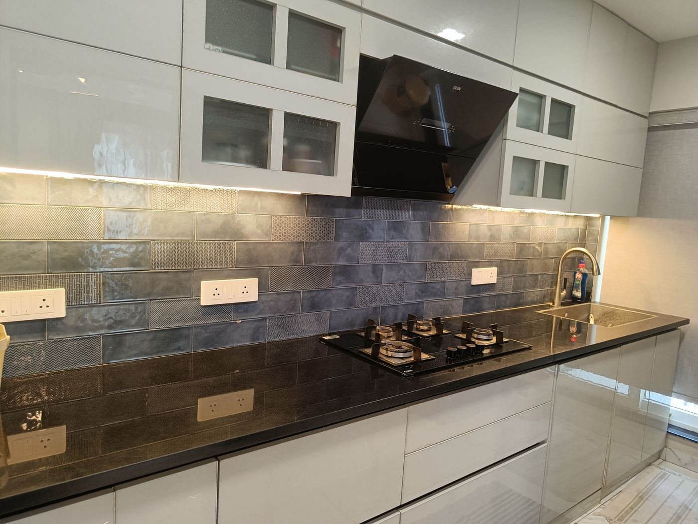 Glossy white modular kitchen with grey tiled backsplash